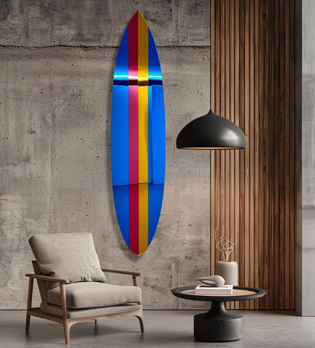 The uniQstiQ Retro Surfboard Wall Art, a mirrored acrylic surfboard wall hanging in 80s pop art style, adds vibrant decor to your modern living room when displayed on a concrete wall beside a chair and table.